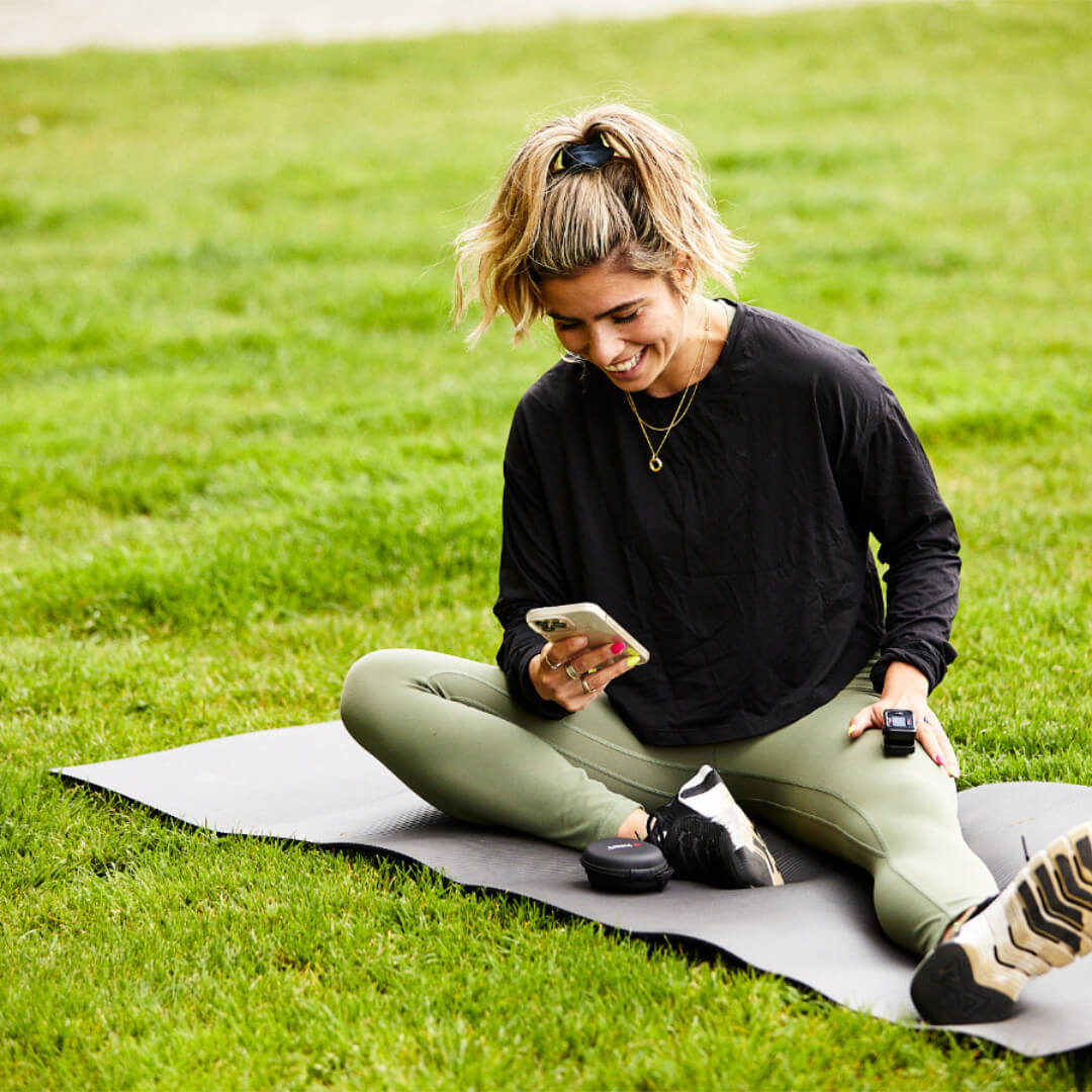 Smiling woman sitting while using iHeart device with her Smartphone