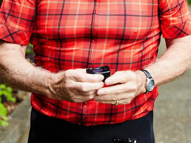 Elder wearing red checker polo holding iHeart device