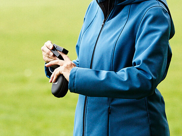 Person wearing blue jacket using iHeart device on index finger